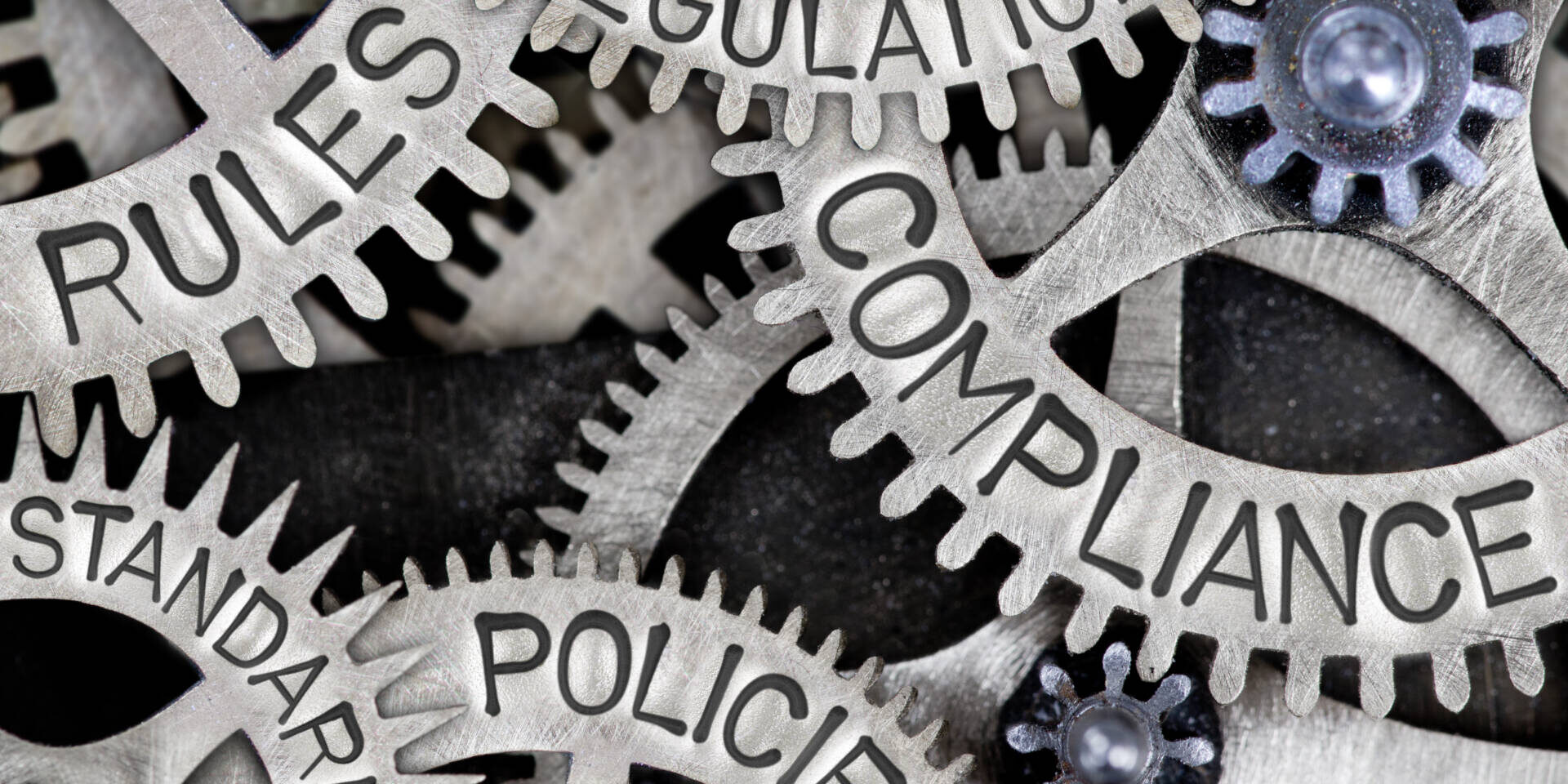 Macro photo of tooth wheels with COMPLIANCE, REGULATIONS, STANDARDS, POLICIES and RULES words imprinted on metal surface